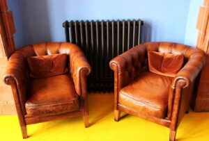 two leather sofas in front of a blue wall and black radiator